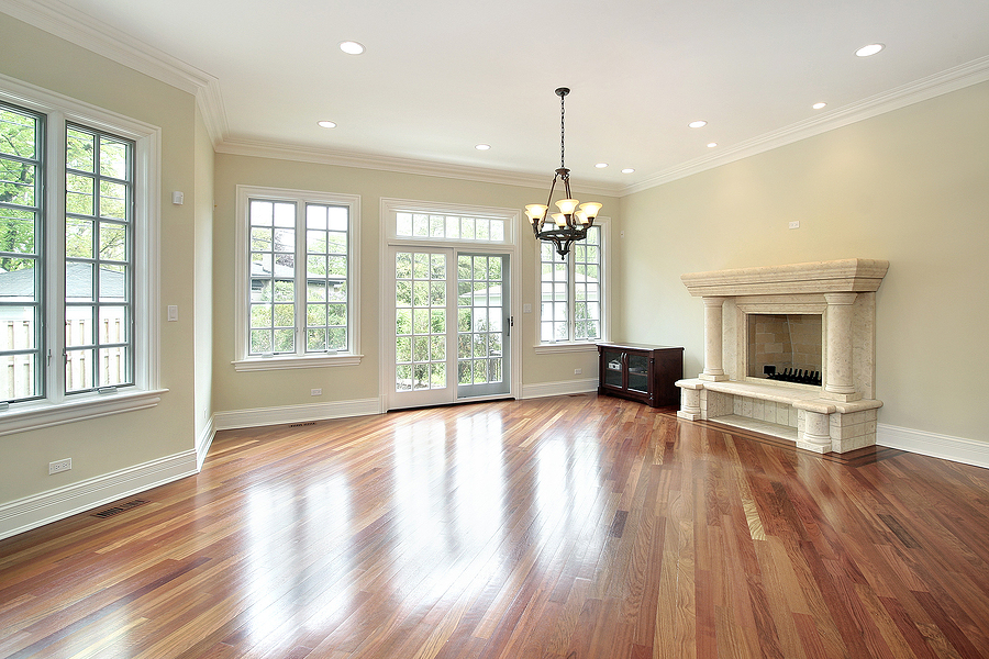 Hardwood flooring in a family room with big windows and a fireplace.