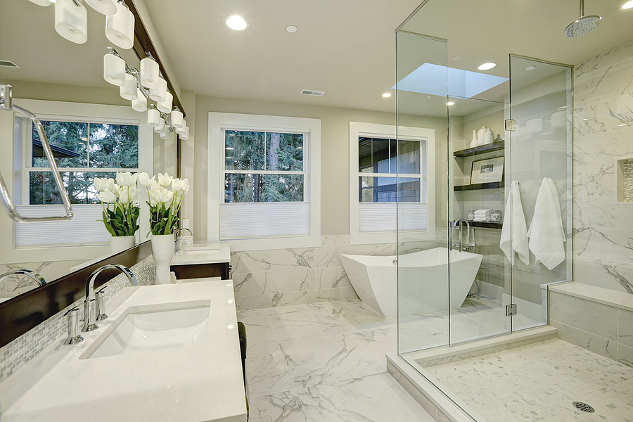 Amazing white and gray marble master bathroom with large glass walk-in shower freestanding tub and skylights on the ceiling.