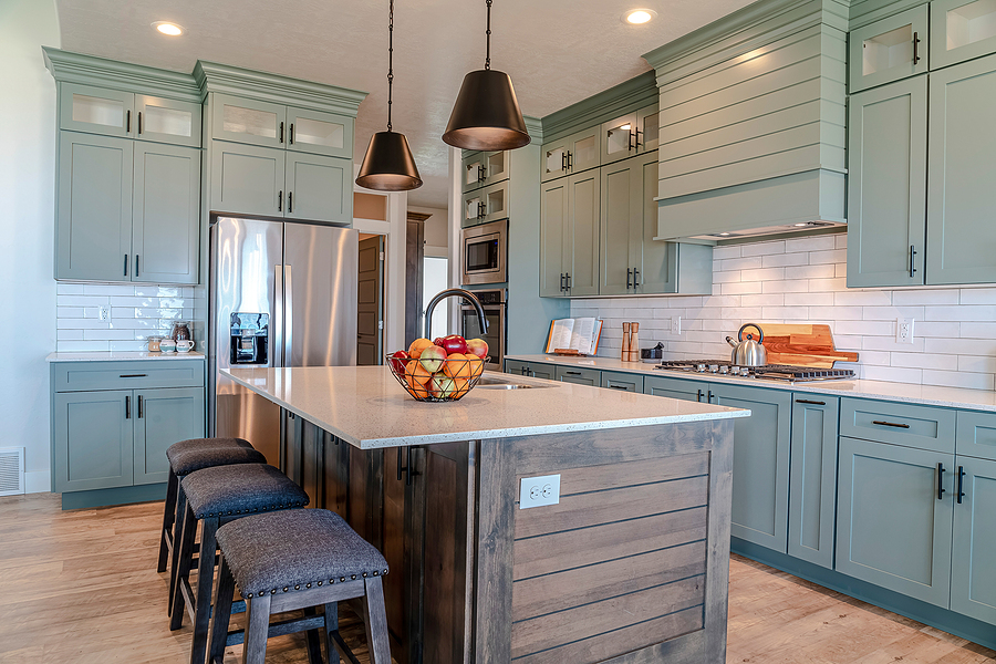 Kitchen island with cushioned stools inside home kitchen with built in cabinets.