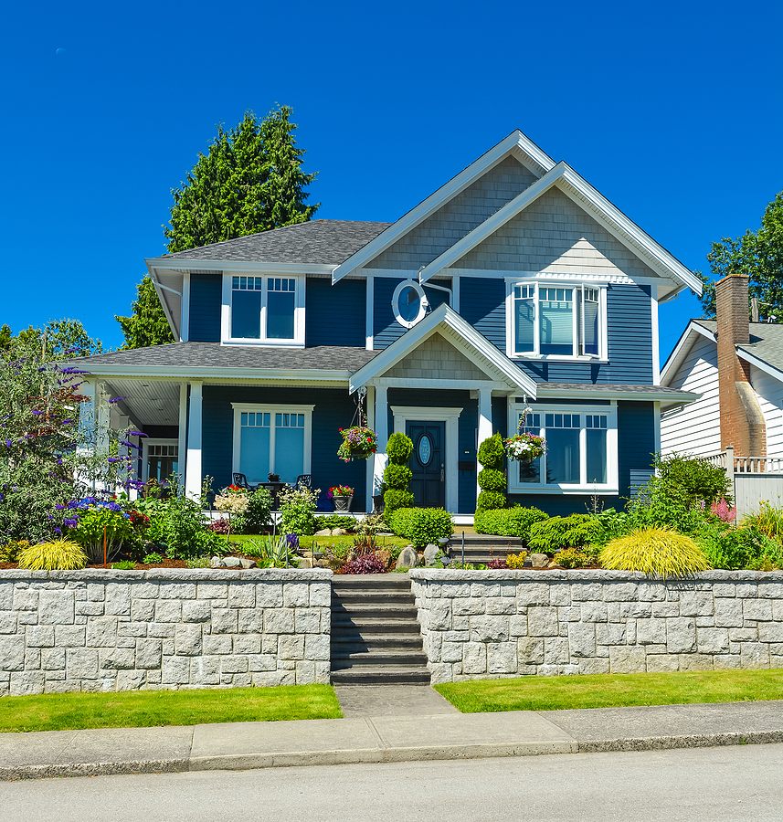 Luxury family house with landscaped front yard on land terrace. Family house on blue sky background