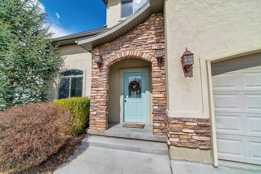 Home with arched stone exterior entryway and glass paned front door with wreath.
