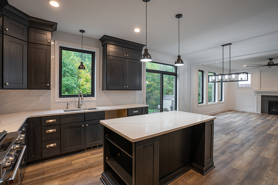 Newly remodeled kitchen with black framed windows, a large center island, and dark painted cabinets.