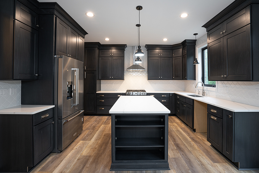 Remodeled kitchen has new black cabinets and new stainless steel appliances installed.
