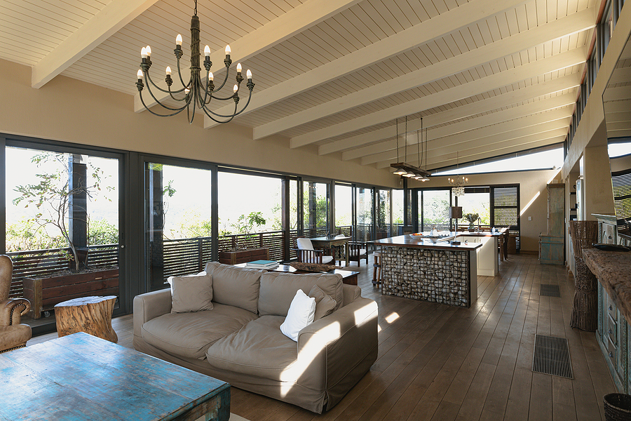 Interior of open plan kitchen diner and living room of comfortable home, with windows to terrace. modern architecture and domestic interior design.