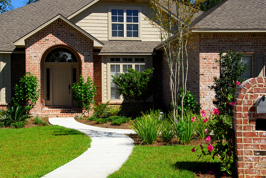 Brick house front with sidewalk and garden landscaping